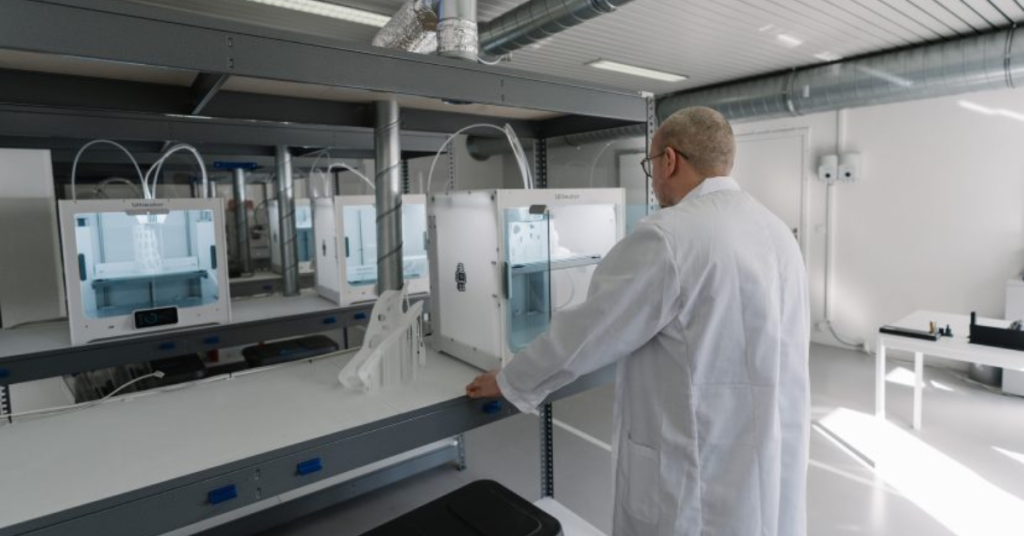 Industrial 3D printing manufacturing lab with multiple printers operating simultaneously as a technician monitors production, showcasing additive manufacturing workflows used in modern factories.