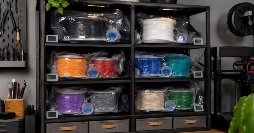 Vacuum-sealed filament spools organized in storage cubbies with desiccant containers and humidity displays.