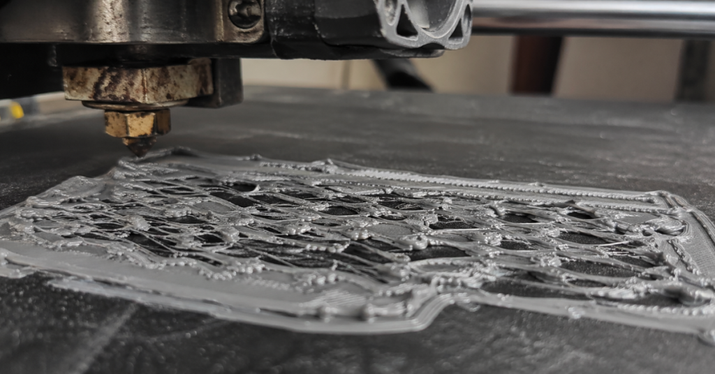 3D printer bed covered with messy overextruded lines and blobs from moisture-affected filament during printing