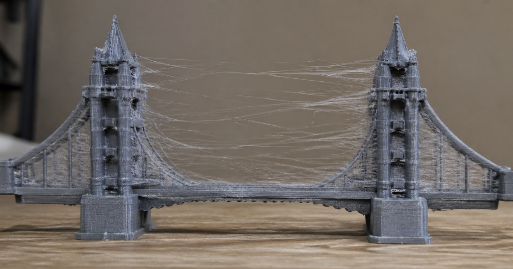 3D printed bridge model showing heavy stringing between towers due to moisture-contaminated filament