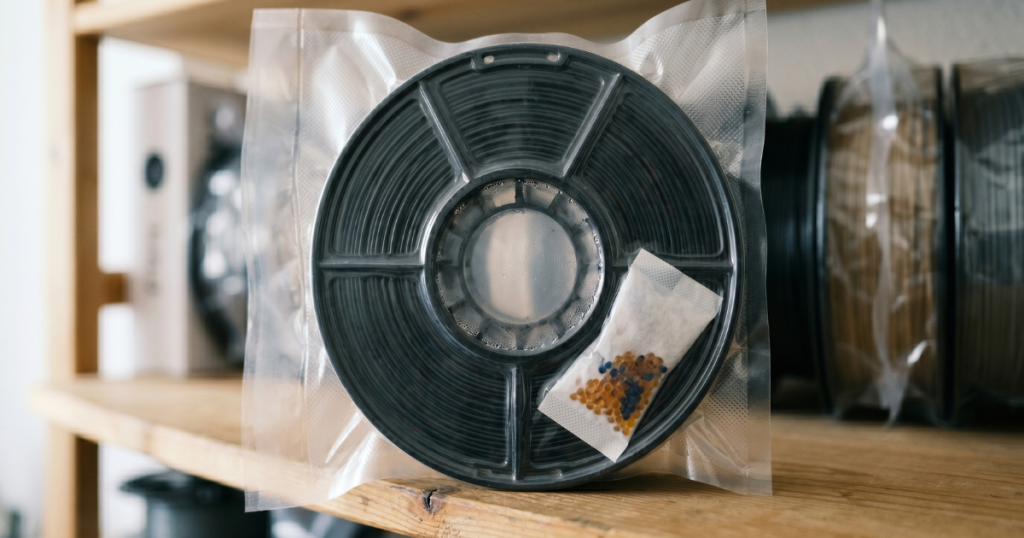 Filament spool stored in a sealed bag showing condensation and moisture exposure near a desiccant pack.